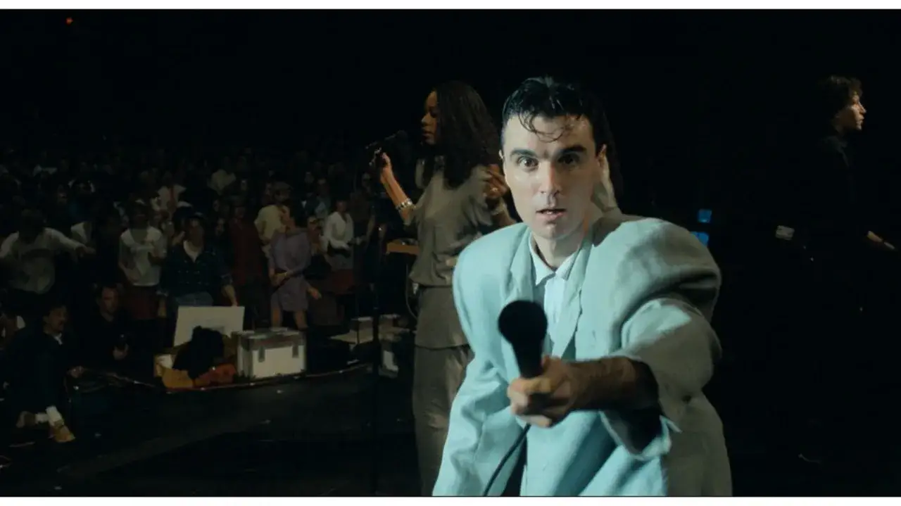 David Byrne z The Cult - Be Free, śpiewa do mikrofonu na tle tłumu.