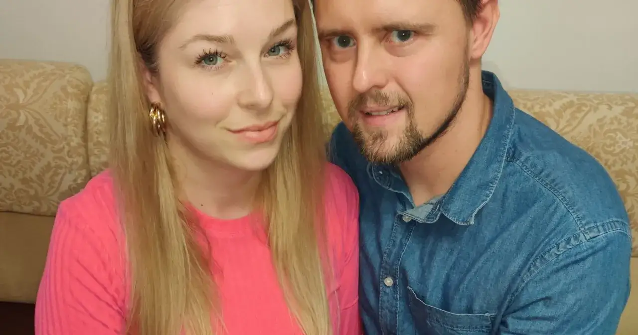 Zbliżenie na twarze pary siedzącej obok siebie na kanapie.