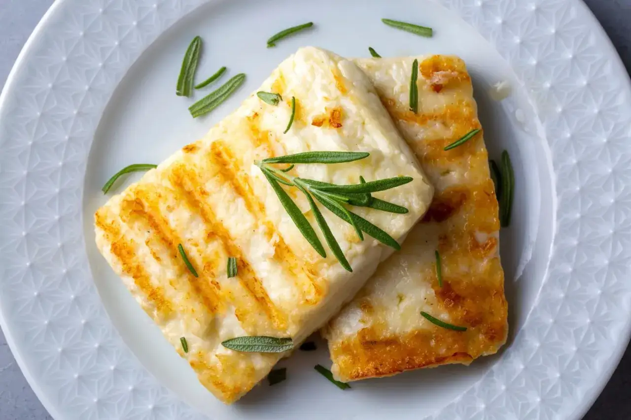Grillowany ser halloumi z rozmarynem na białym talerzu.