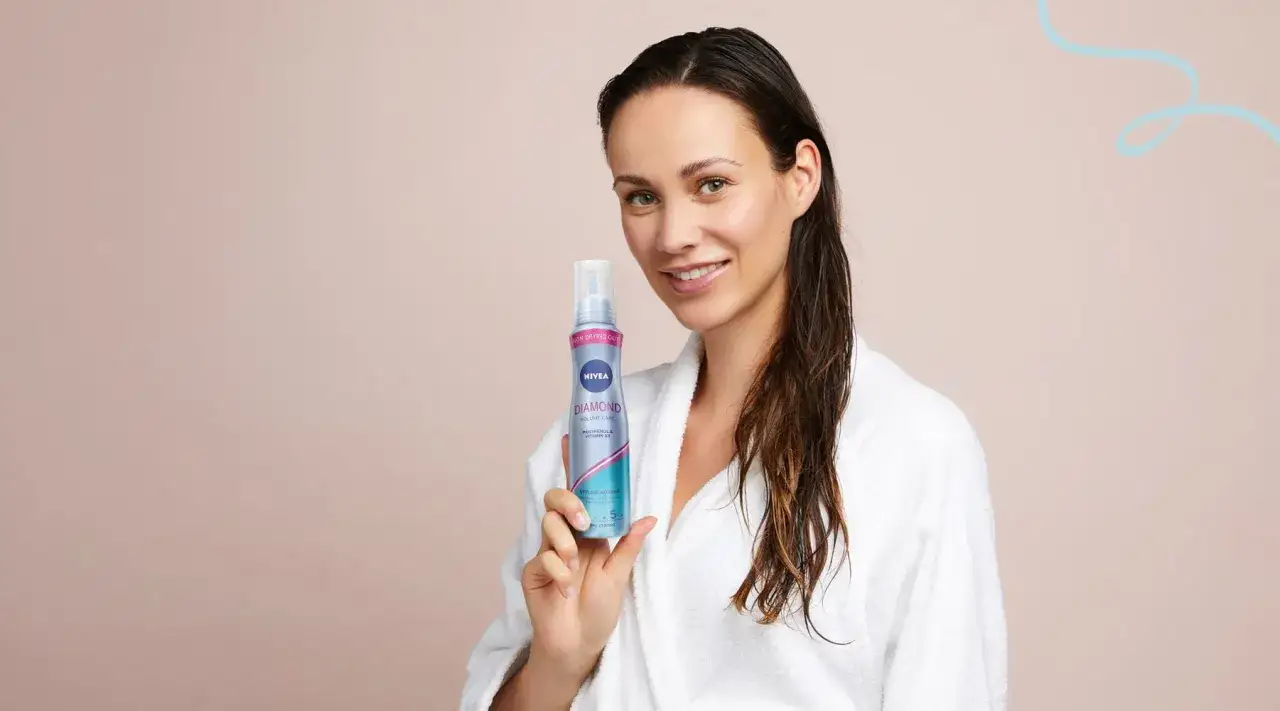 Kobieta w szlafroku trzyma piankę Nivea Diamond. Po zużyciu opakowanie po piance do włosów wyrzuć do plastiku.