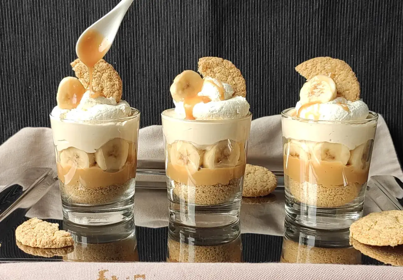 Pyszny deser bananowy przepis w szklaneczkach: warstwy ciastek, karmelu, bananów i bitej śmietany. Idealny na deser!