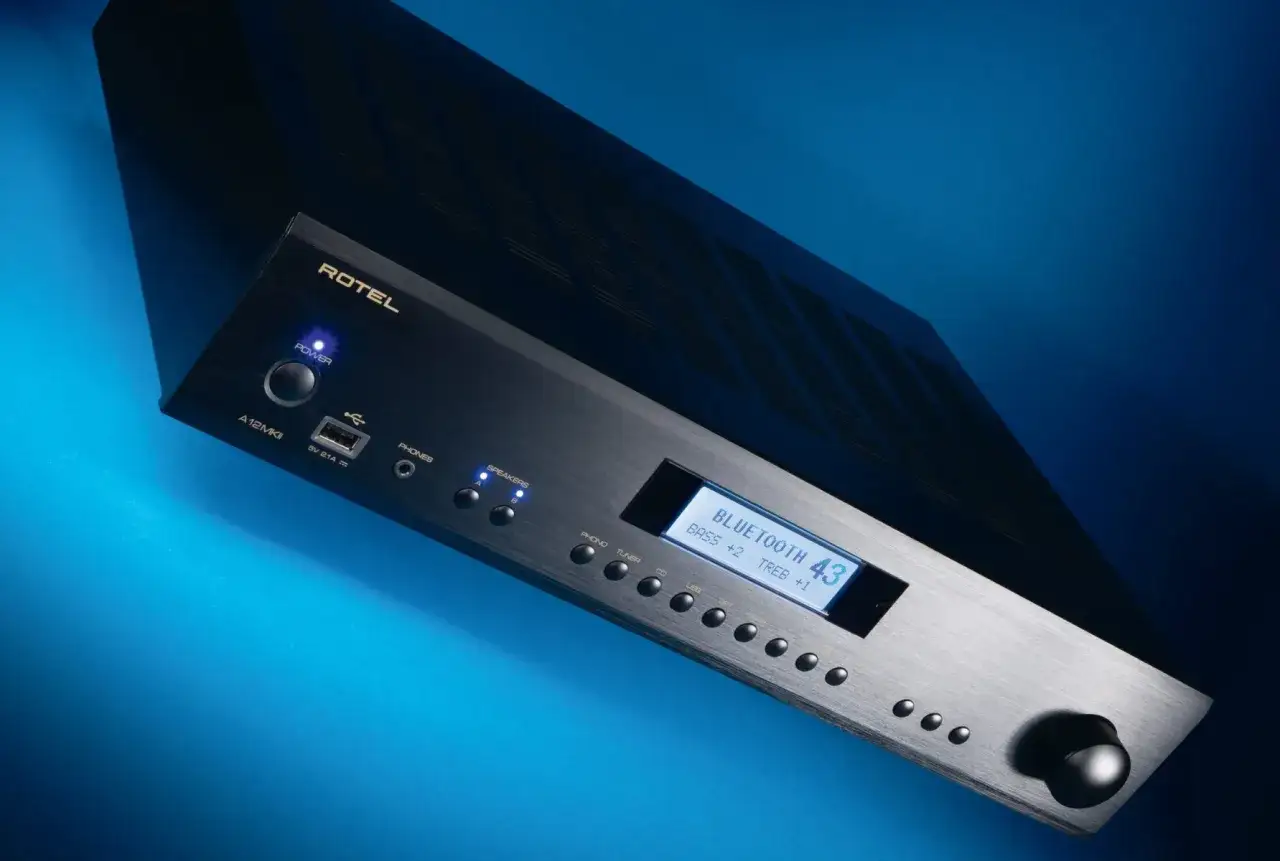 Czarny wzmacniacz Rotel A12 MKII z niebieskim podświetleniem, wyświetlaczem Bluetooth i pokrętłem głośności.