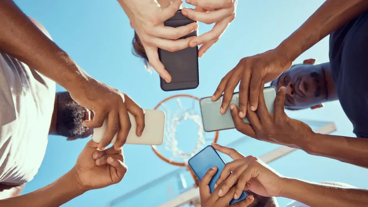 Grupa osób trzyma telefony, jakby omawiali oferty operatorów komórkowych w Polsce.