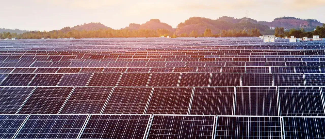 Ogromne pole paneli fotowoltaicznych do 150 kW bez pozwolenia na budowę, lśniące w słońcu na tle gór.