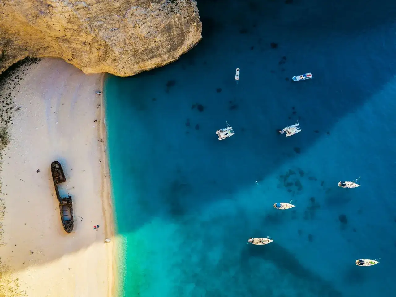W Grecji jest morze, nie ocean. Widok na plażę Navagio z wrakiem statku i łodziami na turkusowej wodzie.