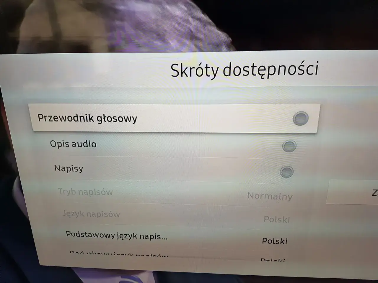 Menu telewizora z opcjami "Przewodnik głosowy", "Opis audio", "Napisy", "Tryb napisów", "Język napisów".