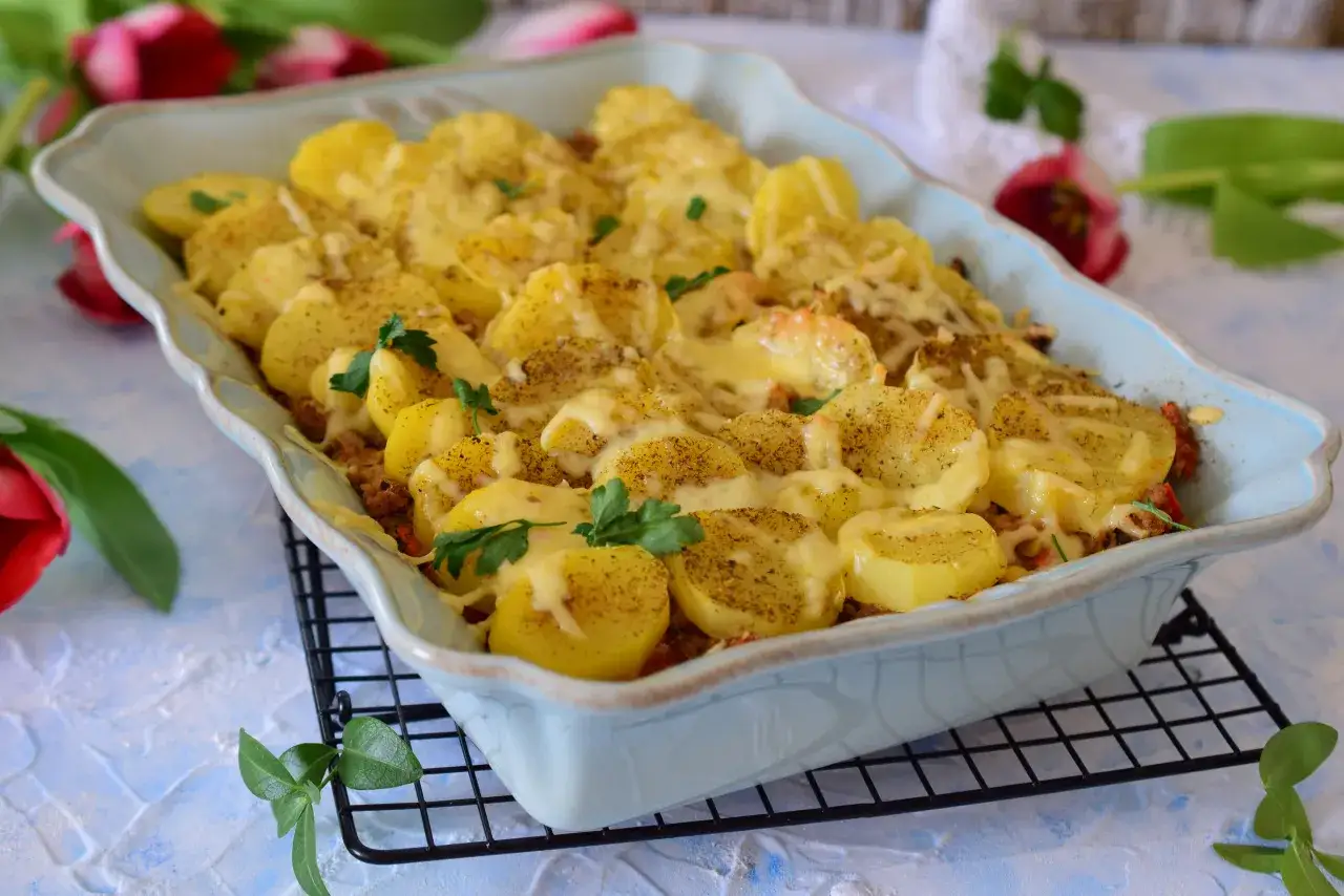 Zapiekanka ziemniaczana z mięsem mielonym, posypana serem i ziołami, w niebieskiej brytfance.