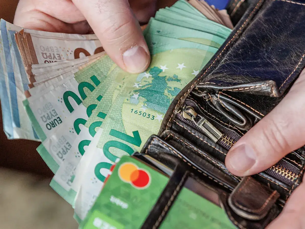 Dłonie trzymające portfel z banknotami euro. Od 2015 roku jaka waluta jest na Litwie? Euro.