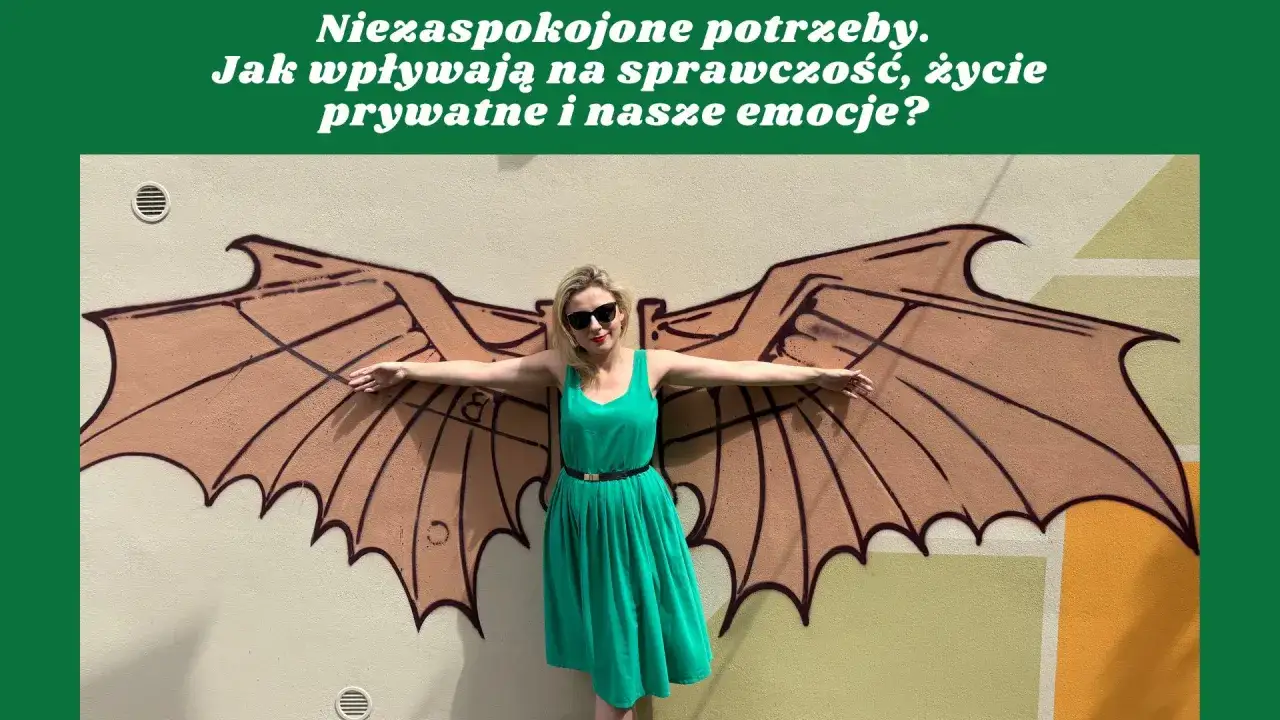 Kobieta w zielonej sukience stoi przed muralem z brązowymi skrzydłami.