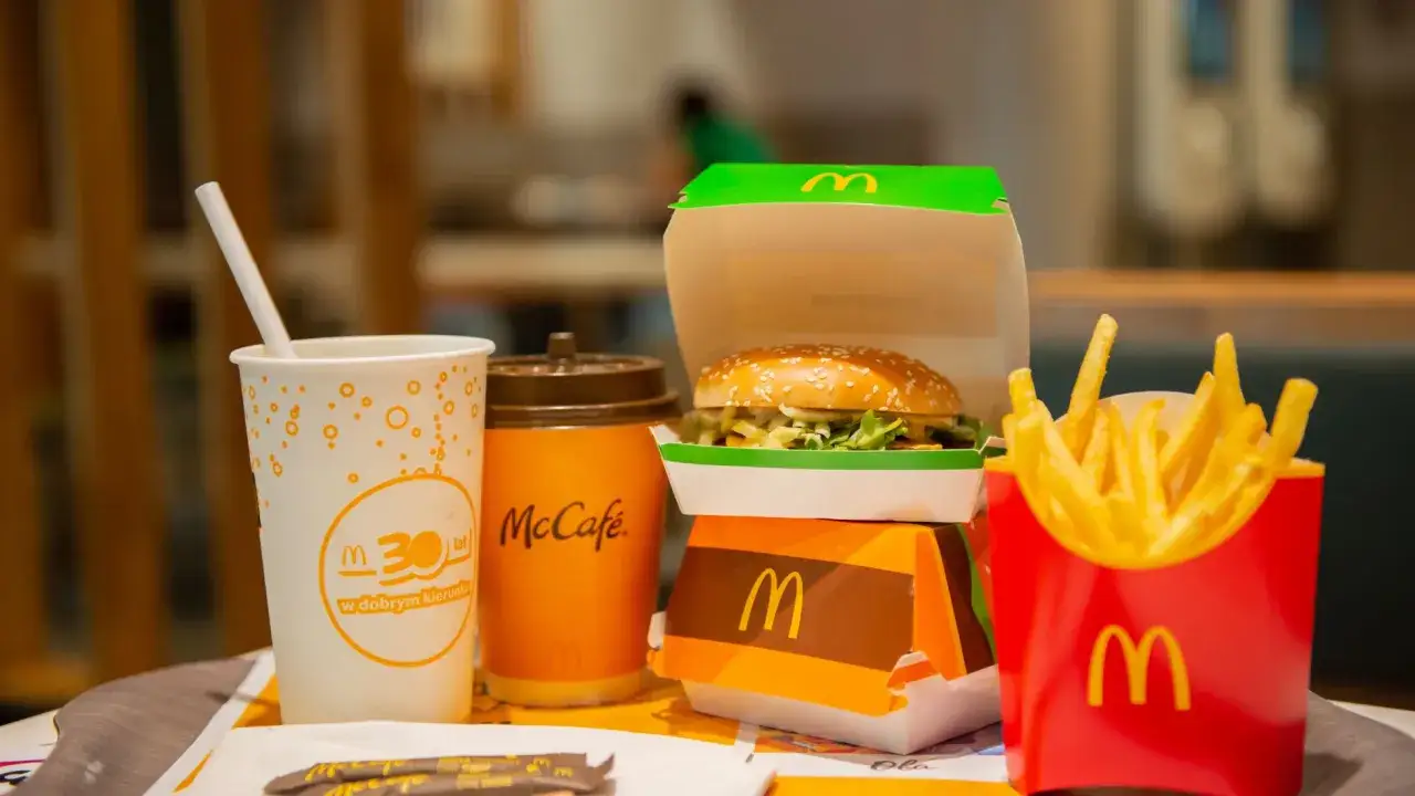 Burger, frytki, napój i kawa McCafe na tacy.