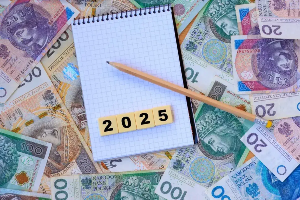 Notatnik z ołówkiem i kafelkami z cyframi "2025" na tle polskich banknotów.