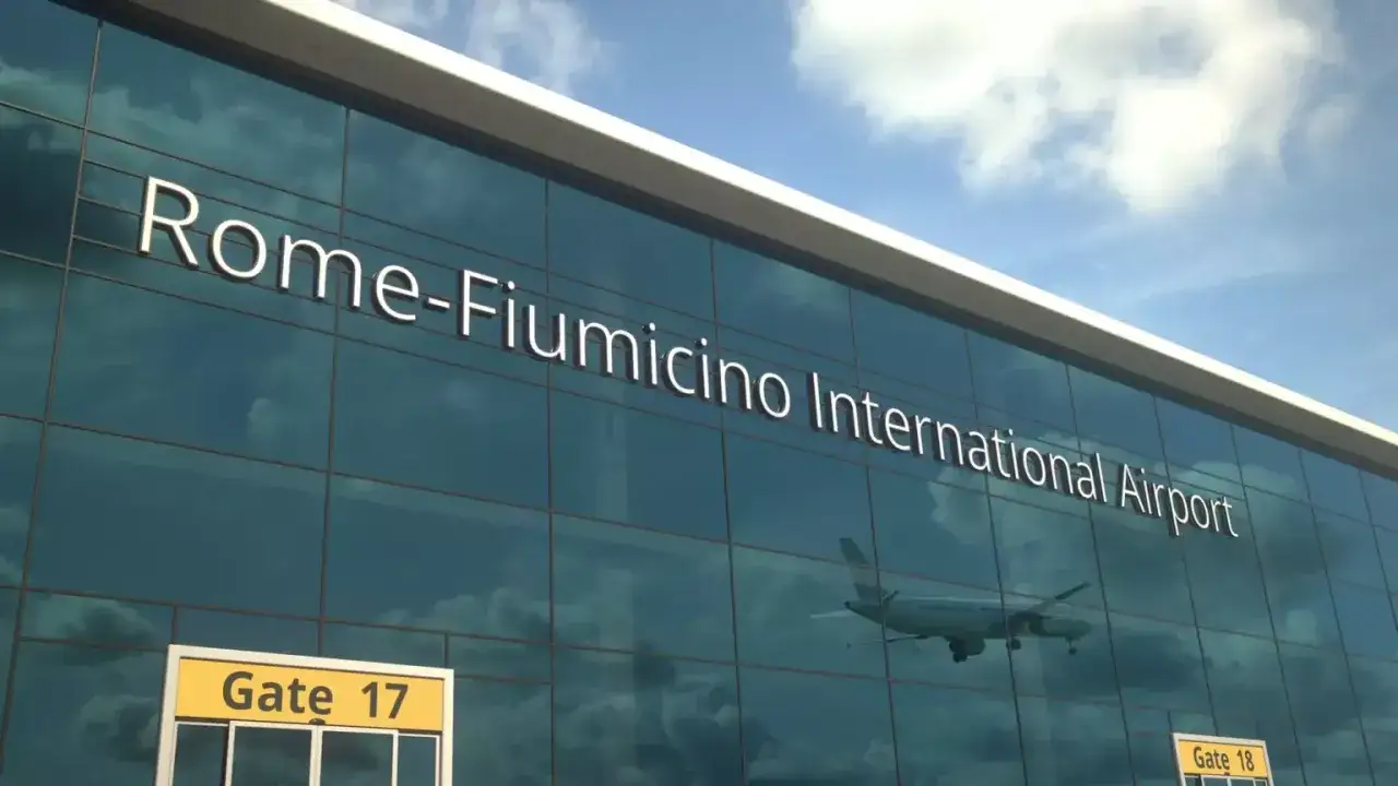 Lotnisko Rzym Fiumicino. Jak dojechać do centrum? Widok na nowoczesny budynek lotniska z napisem "Rome-Fiumicino International Airport" i odbijającym się samolotem.