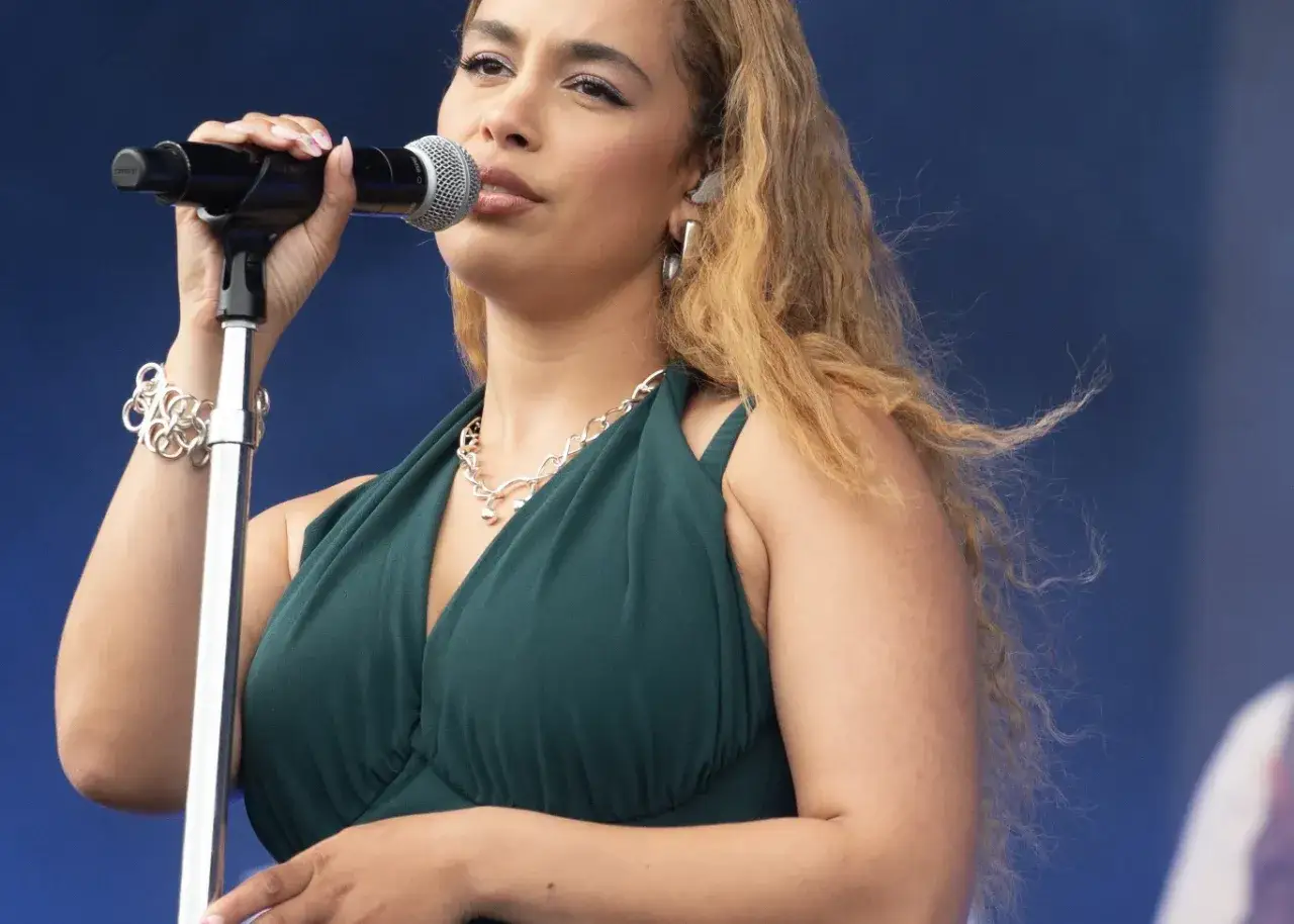 Maju maj, kto śpiewa? Młoda artystka w zielonej sukience, z mikrofonem w dłoni, czaruje publiczność.