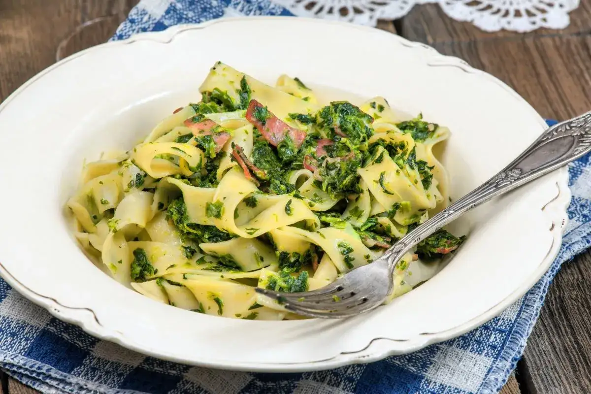 Pappardelle z boczkiem i szpinakiem, danie pełne smaku, podane na talerzu z widelcem.
