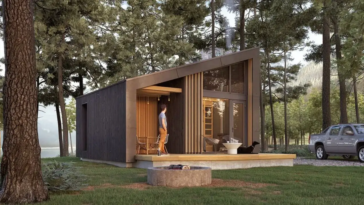 Nowoczesne domki letniskowe bez pozwolenia w otoczeniu lasu. Czarny domek z drewnianym tarasem, miejscem na ognisko i widokiem na góry.