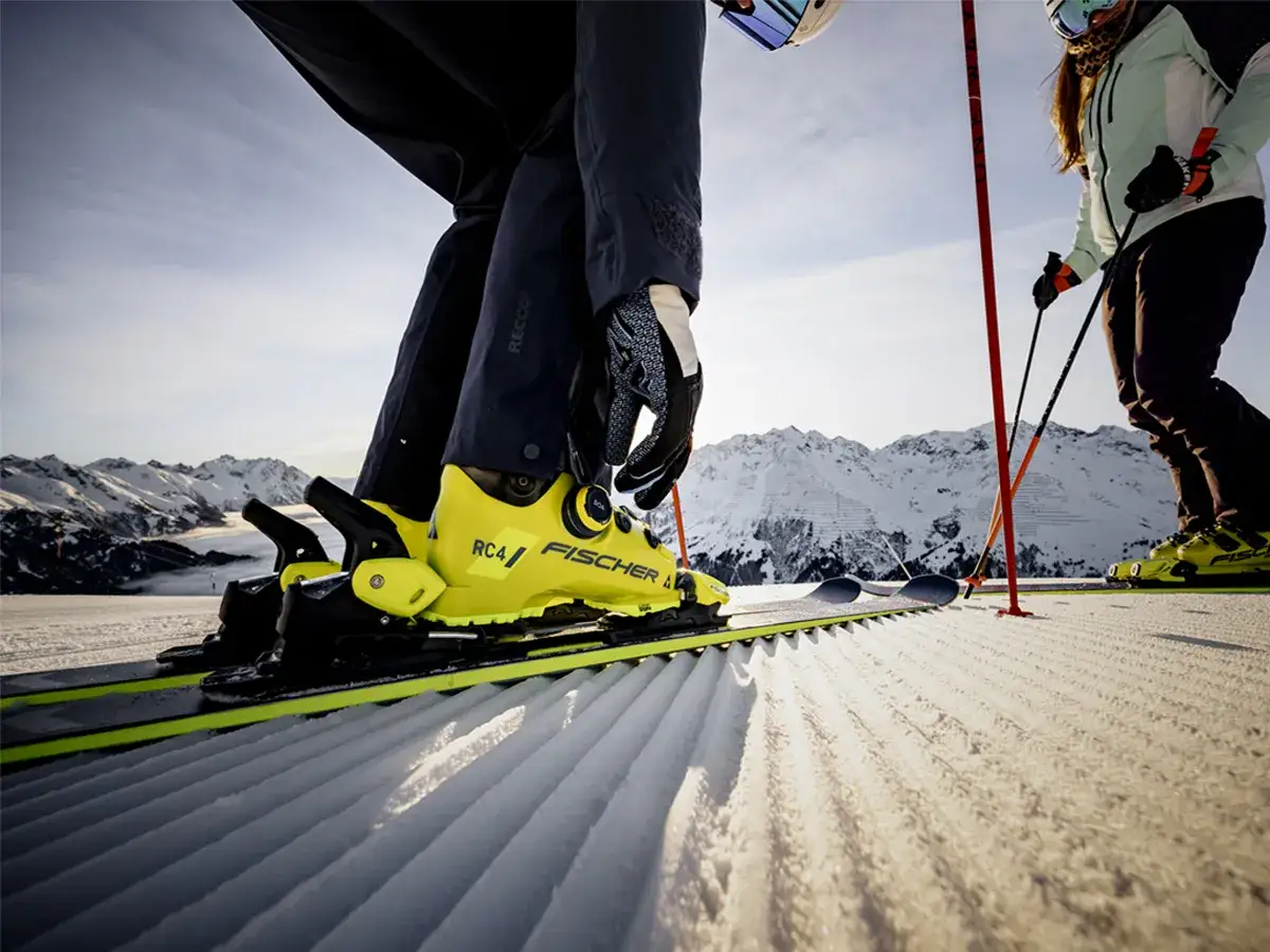 Zbliżenie na żółte buty narciarskie Fischer RC4 na nartach na stoku.
