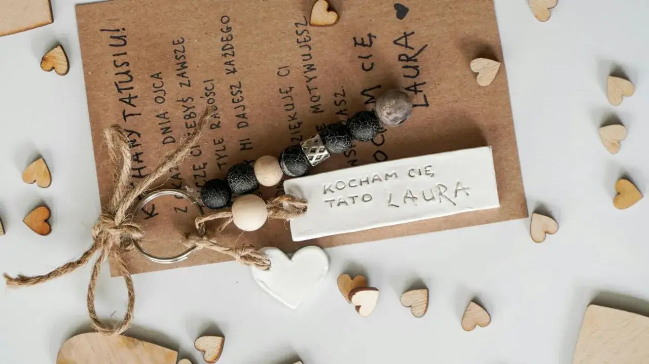 Brelok z napisem "Kocham Cię Tato Laura" i serduszkami. Symbolizuje miłość i wdzięczność, co oznaczają klucze na roczek dla taty.