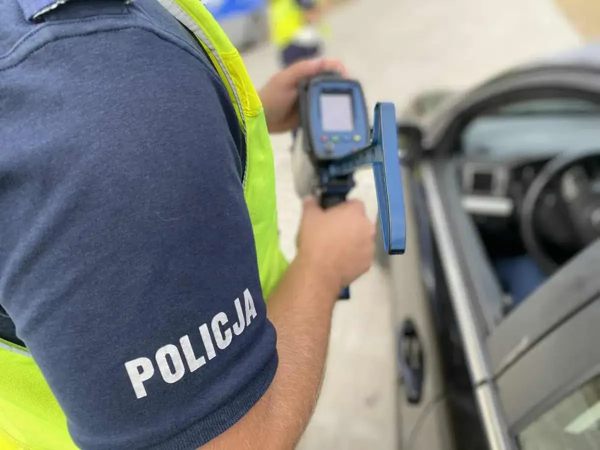 Policjant mierzy prędkość samochodu radarem.