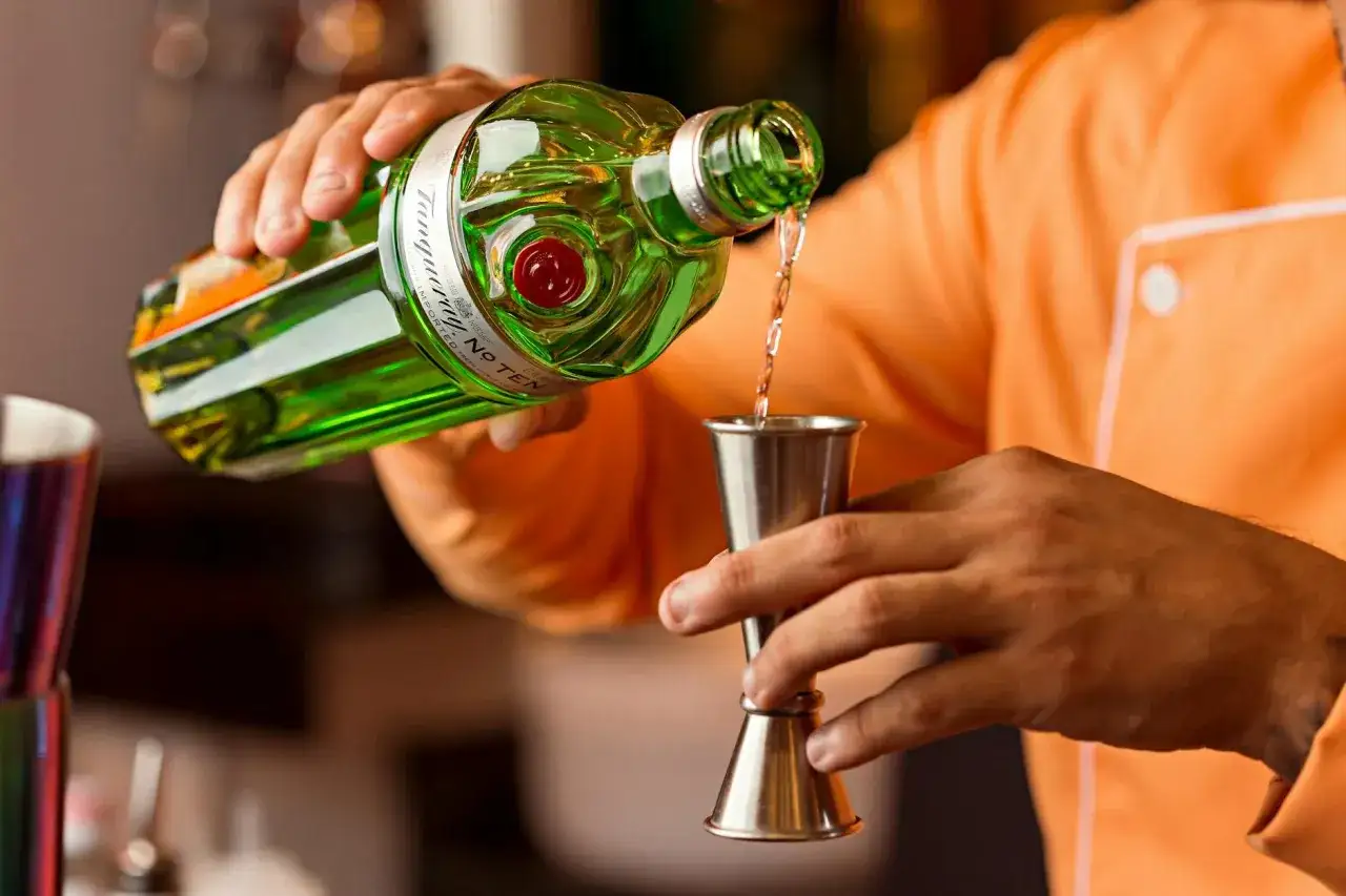 Barman nalewa gin do jiggera. Standardowy shot to 45 ml, a jigger barmański ma proporcje 25/50 ml.