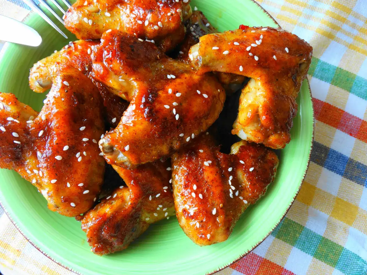 Skrzydełka w miodzie i sosie sojowym, posypane sezamem, na zielonym talerzu. Kwestia smaku, która zachwyca!