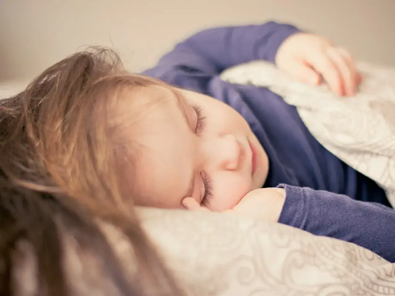 Dziecko śpi spokojnie, choć czasem **moczenie nocne na tle nerwowym** może zakłócać sen.