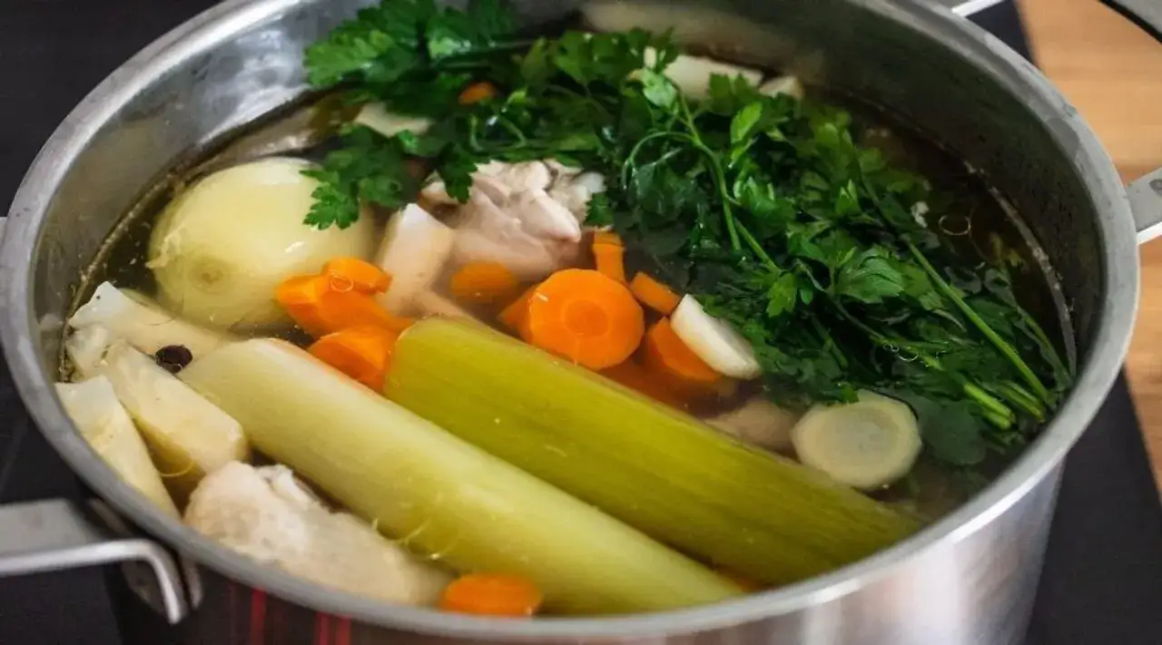 Gotujesz rosół? W garnku bulion z warzywami: marchewka, seler, por, cebula i natka pietruszki. Idealne składniki, by mrozić warzywa na rosół.