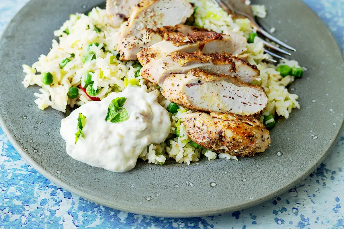 Pyszny kurczak z ryżem i groszkiem, idealny pomysł, co zrobic z ryzem po ugotowaniu. Podany z sosem jogurtowym.