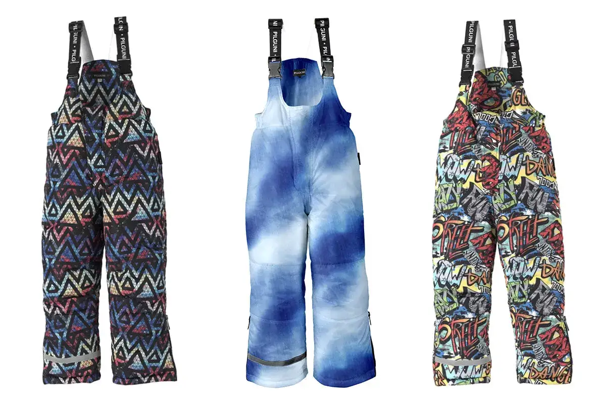 Trzy dziecięce kombinezony narciarskie na białym tle: wzór geometryczny, tie-dye i graffiti.