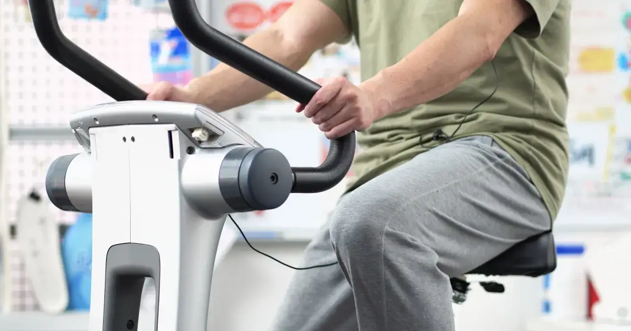 Osoba ćwiczy na rowerku stacjonarnym. Dowiedz się, ile jeździć na rowerku stacjonarnym, aby osiągnąć swoje cele.