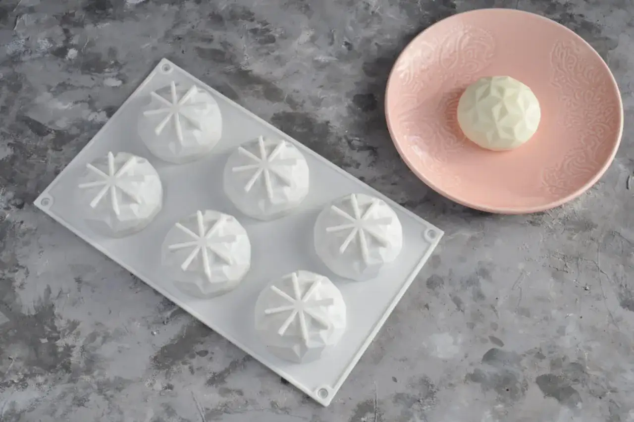 Forma silikonowa z sześcioma wypukłymi ciastkami, idealna do przepisu na ciasto do formy silikonowej. Jedno ciastko na różowym talerzyku.