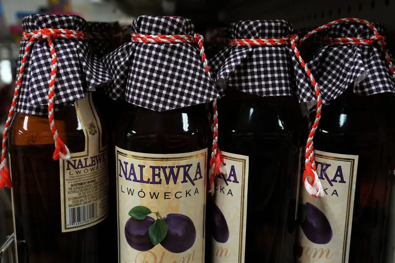 Butelki nalewki lwóweckiej z etykietami i ozdobnymi sznurkami.