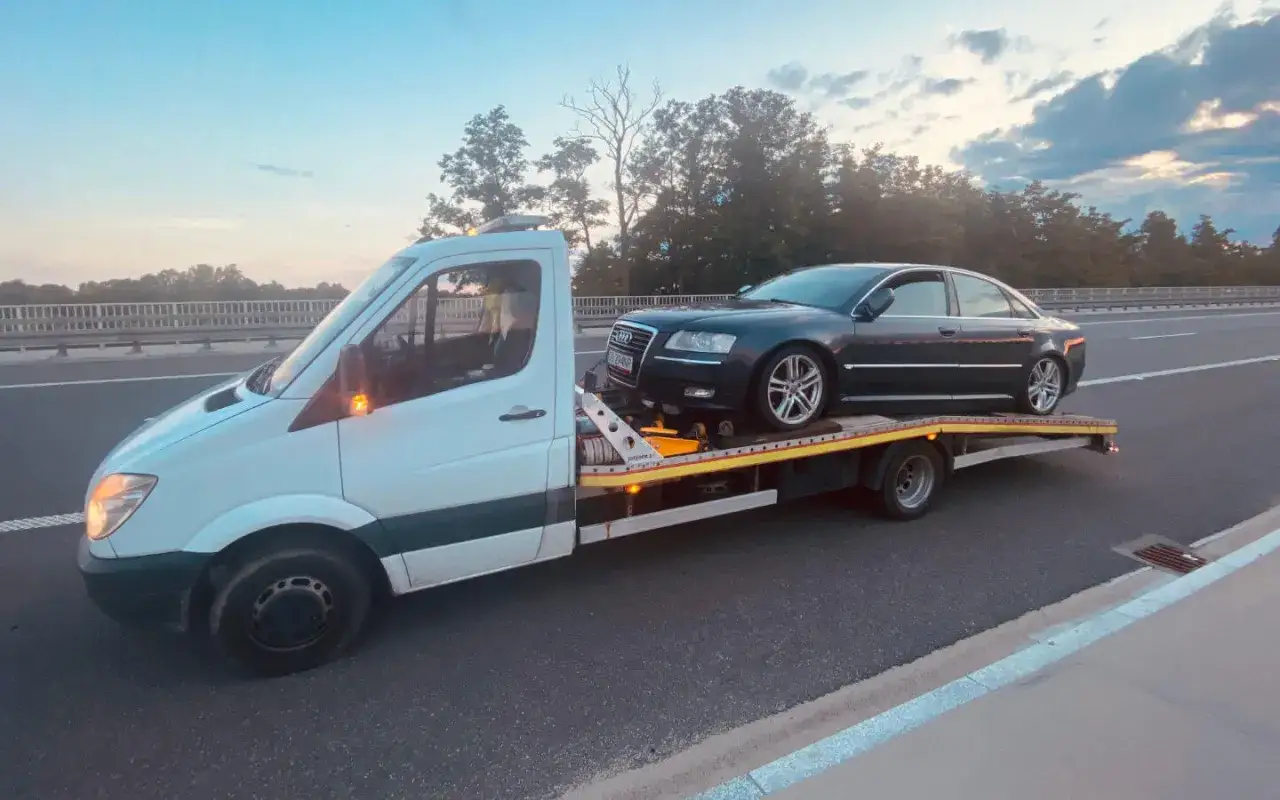 Laweta z ciemnym Audi na pokładzie jedzie po autostradzie. Zastanawiasz się, ile wazy laweta z takim ładunkiem?
