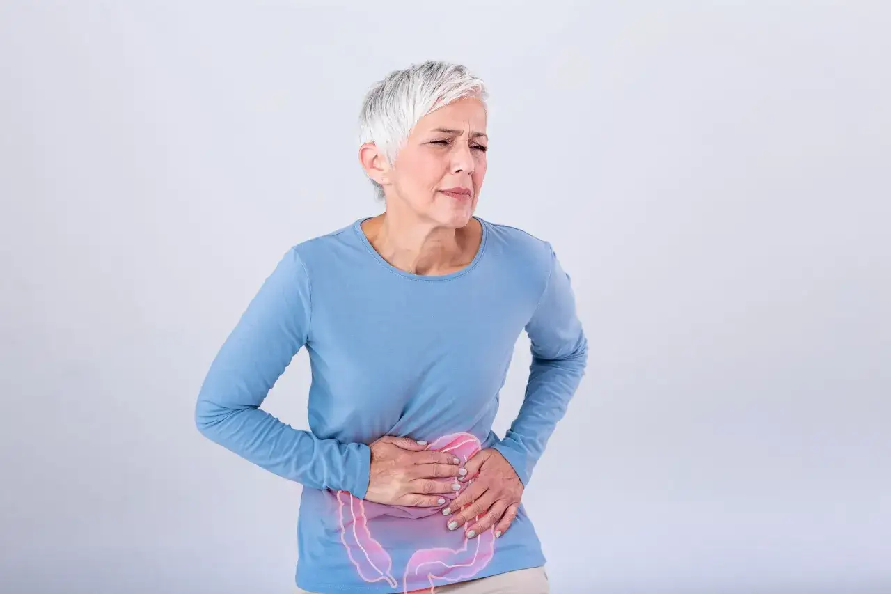 Starsza kobieta z bólem brzucha, z zaznaczonymi jelitami.