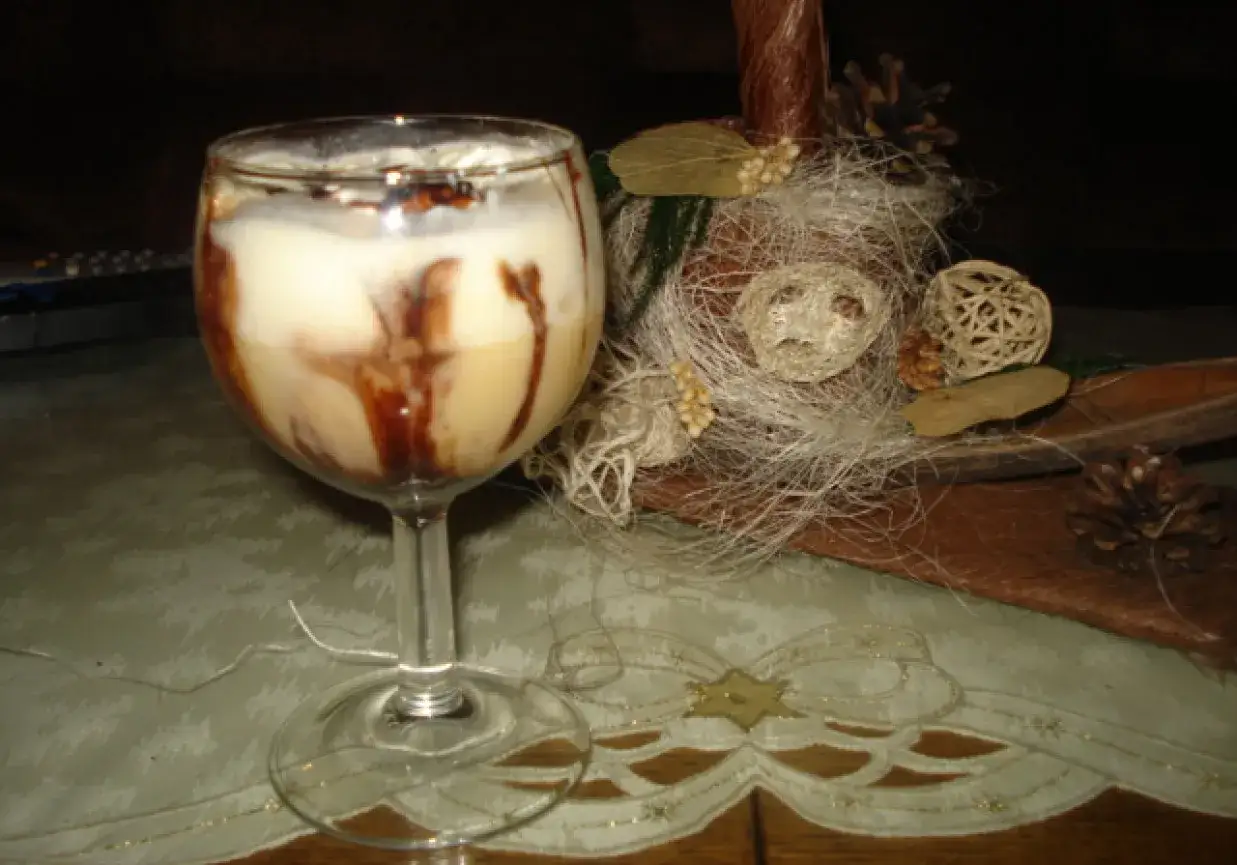 Pyszny drink z adwokatem, udekorowany czekoladą, na tle świątecznych ozdób.
