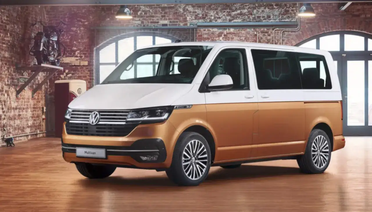 Biało-złoty bus osobowy Volkswagen Multivan w garażu z ceglaną ścianą.
