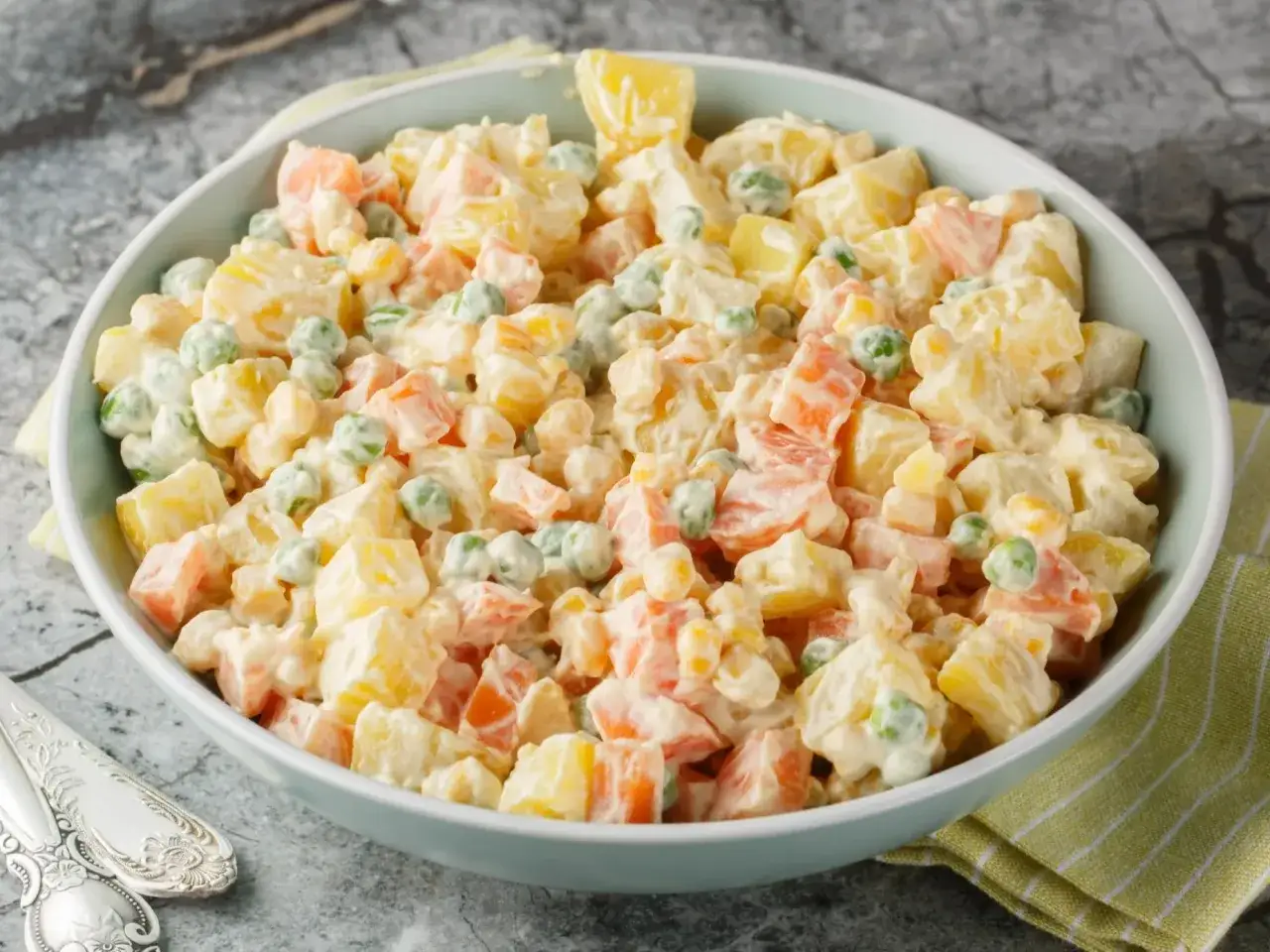 Sałatka jarzynowa z jogurtem w misce, z widocznymi ziemniakami, marchewką i groszkiem.