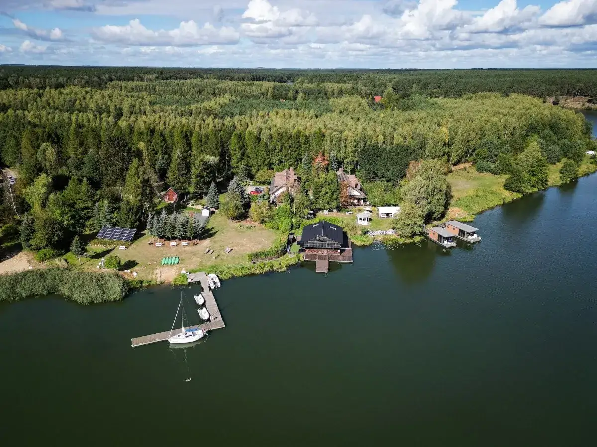 Widok z lotu ptaka na jezioro, las i domki nad wodą.