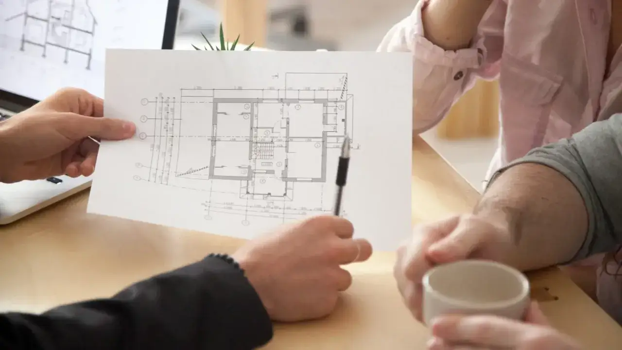 Architekt omawia z klientami projekt domu, wskazując na planowaną powierzchnię netto budynku.