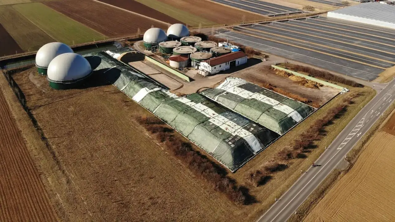Duże, białe kopuły i zielone, zakryte pryzmy na terenie biogazowni. Czy biogazownia śmierdzi? Zależy od wiatru i odległości.
