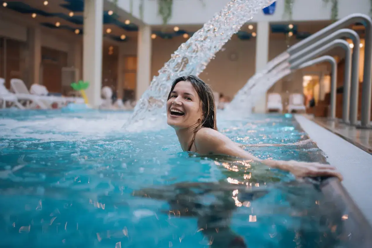 Szczęśliwa kobieta w basenie z wodospadem. Czy które termy lepsze: Bukowina czy Bania?