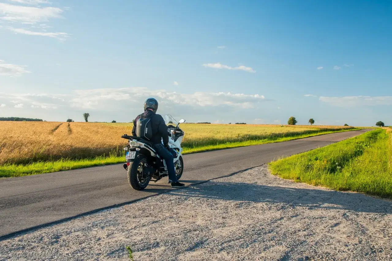 Motocyklista na tle pól pszenicy, odkrywa malownicze trasy motocyklowe mazowieckie.