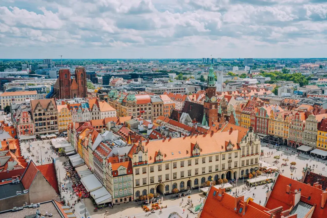 Wrocław słynie z kolorowych kamienic na Rynku i wież kościelnych. Widok z lotu ptaka na tętniące życiem miasto.