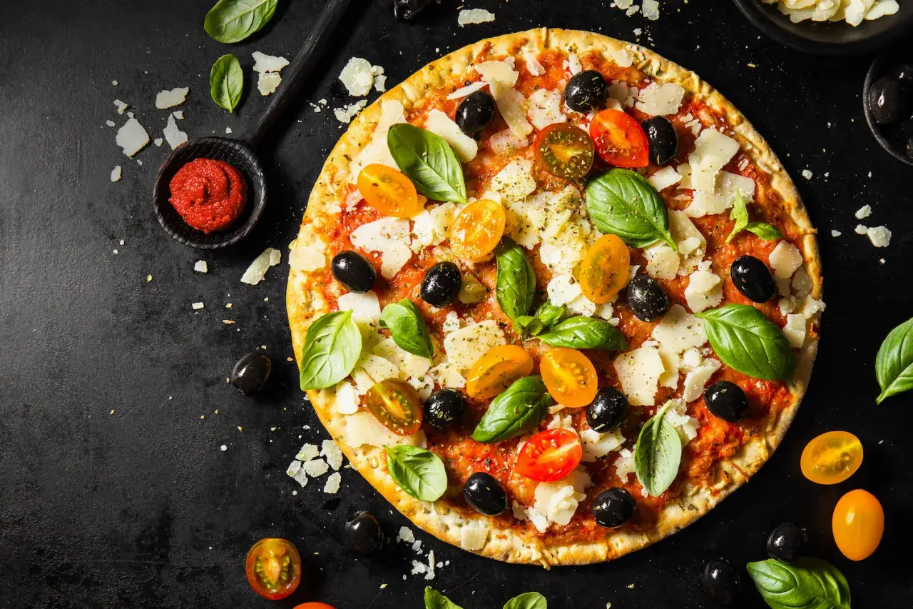 Pizza z pomidorkami, oliwkami i bazylią. Pomidorowe pesto to niezbędny dodatek smakowy włoskiej pizzy.