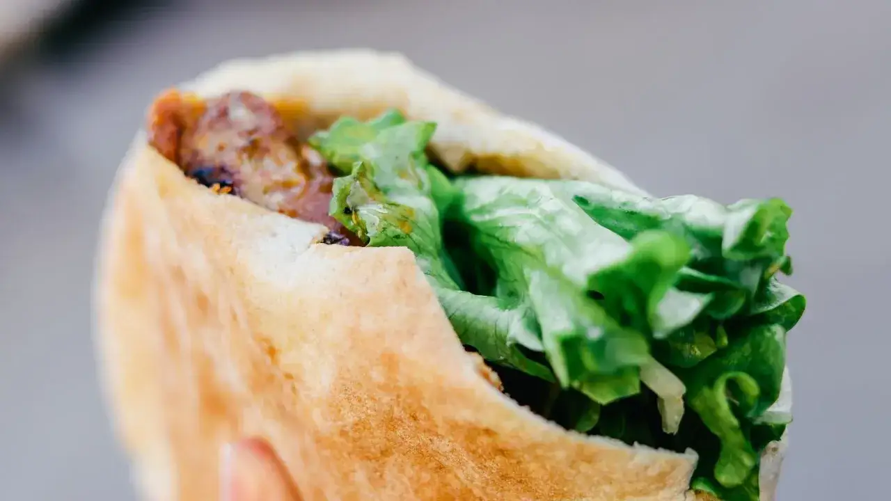 Kebab w bułce z mięsem i świeżą sałatą.