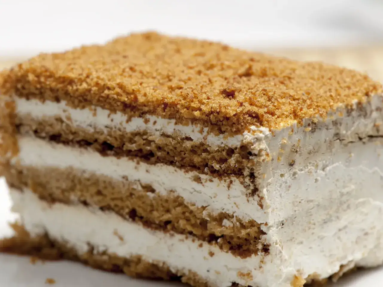 Tranche de gâteau aux couches de biscuit et de crème, saupoudrée de miettes.
