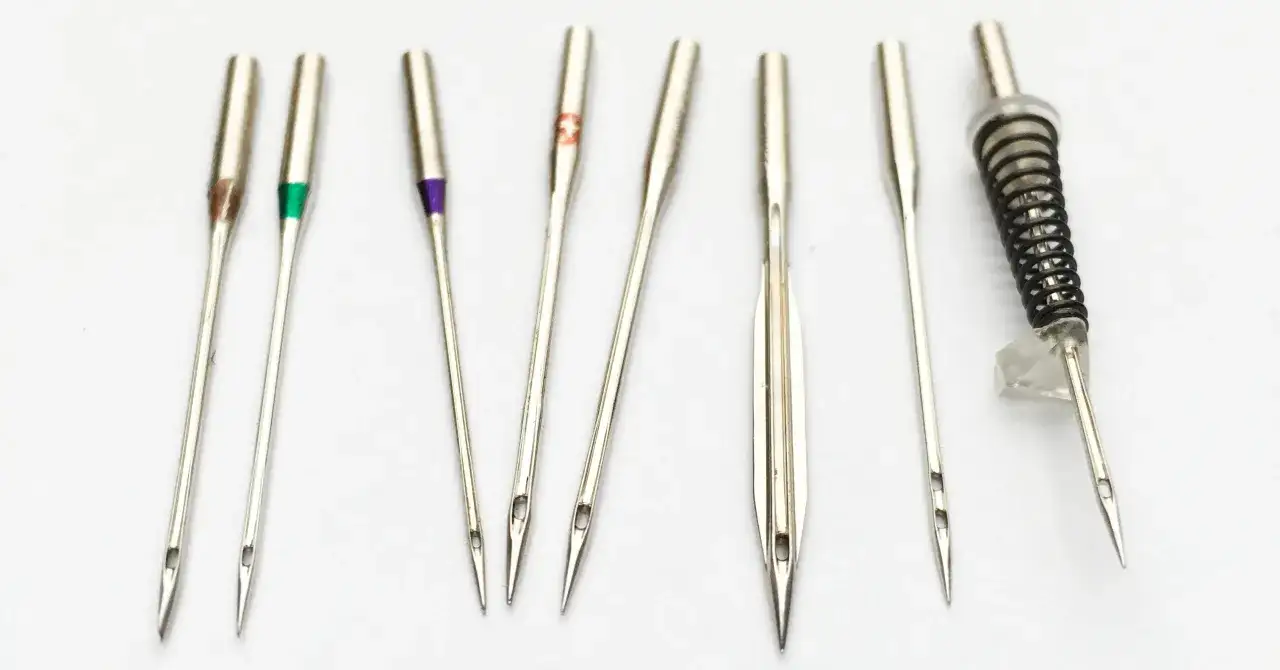 Zestaw igieł do maszyny, w tym igła 90/14 do szycia średnich materiałów. Różne kolory na trzonkach oznaczają rozmiar.