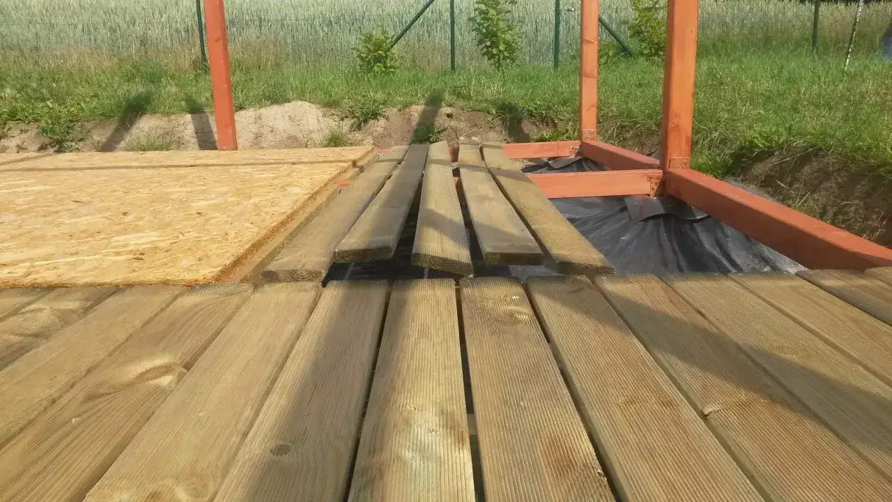 Drewniana konstrukcja altany w trakcie budowy, deski tarasowe i płyta OSB.