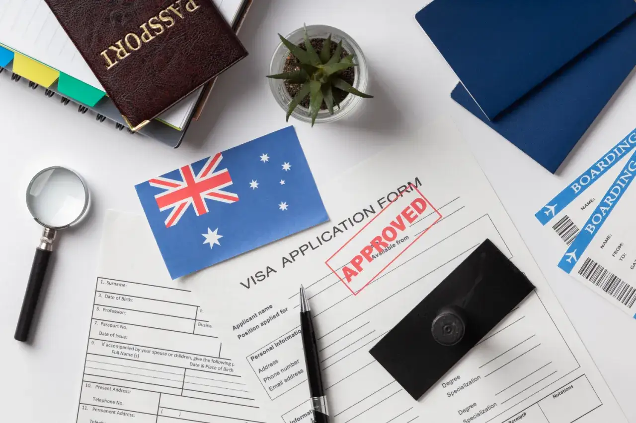 Paszport, formularz wizowy z pieczątką "APPROVED", flaga Australii, bilety lotnicze.