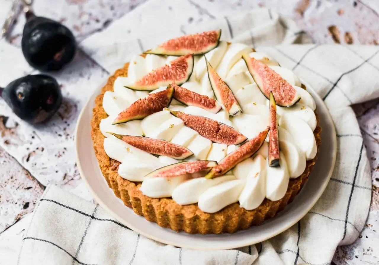 Tarte aux figues fraîches et crème fouettée, décorée de feuilles d'or.