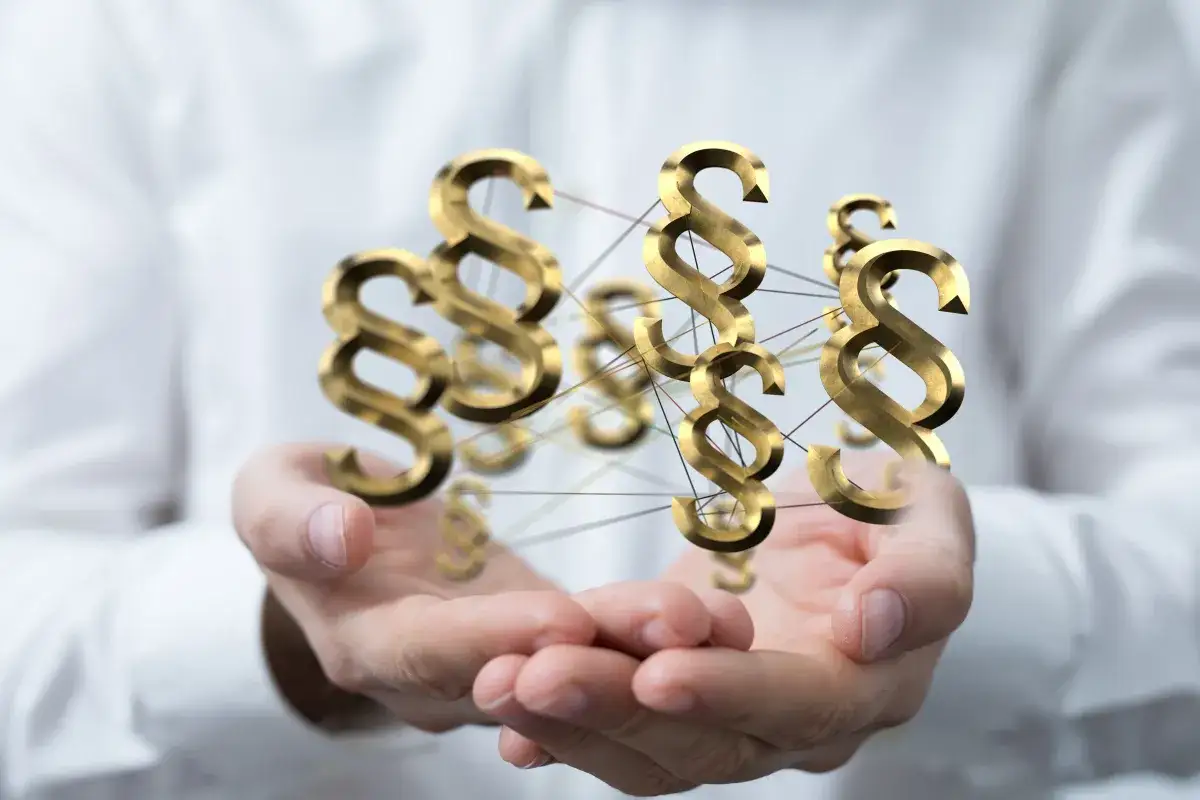 Złote paragrafy unoszą się nad dłońmi. Zastanawiasz się, ile kosztuje adwokat z urzędu?